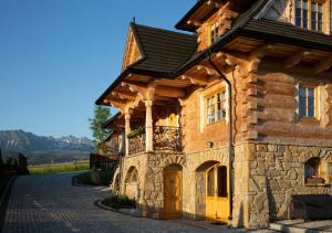 una casa in pietra con tetto nero e porte gialle di Tatra Góral Ski Apartament a Murzasichle