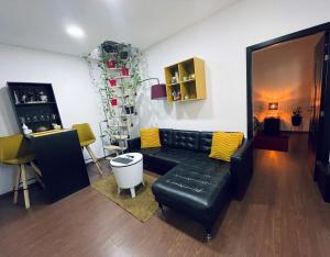 City Garden Apartments في بوخارست: غرفة معيشة مع أريكة جلدية سوداء ووسائد صفراء