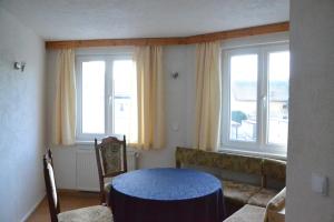 a room with a blue table and two windows at Pension Altwahnsdorf in Radebeul