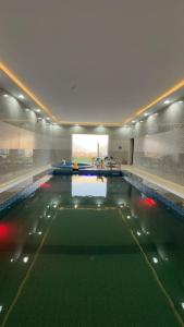 a large swimming pool with green water in a building at شالية الموج الازرق قسمين in Hafr Al Baten