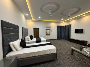 ein Hotelzimmer mit 2 Betten und einem TV in der Unterkunft Green Land Hotel Lahore in Lahore
