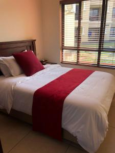 a bedroom with a large bed with a red and white blanket at Lily Park Complex in Rustenburg