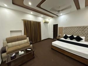 a bedroom with a bed and a chair in it at Green Land Hotel Lahore in Lahore