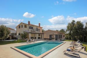 a swimming pool with chairs and a house at Villa PERLA VERDE in Labin
