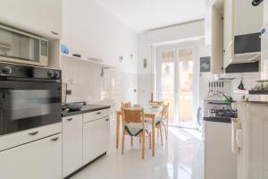 a kitchen with white cabinets and a table with chairs at Castelletto Roomy & Functional Flat in Genoa