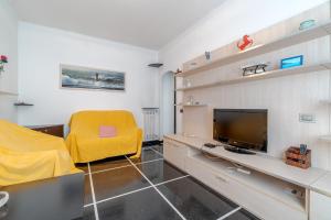 a living room with a yellow chair and a television at Castelletto Roomy & Functional Flat in Genoa