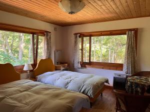 2 Betten in einem Schlafzimmer mit 2 Fenstern in der Unterkunft Ohisama House in Rusutsu