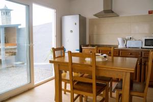 a kitchen with a wooden table with chairs and a kitchen with a window at Beach front flats in São Vicente