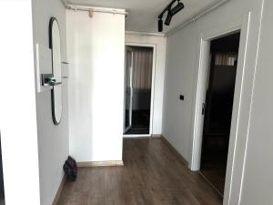 - un couloir avec des murs blancs, du parquet et un miroir dans l'établissement Luxury Apartment with Garden right by sea, à Mudanya