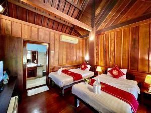 two beds in a room with wooden walls at Lakhang Thong Hotel in Luang Prabang