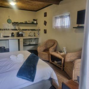 a bedroom with a bed and two wicker chairs at Bedrock- Executive Self Catering Room in Cape Town