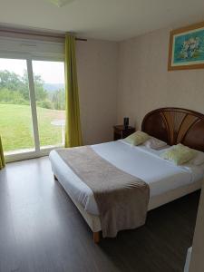 a bedroom with a bed and a large window at Logis Hotel La Bergerie in Saint-Pierre-Lafeuille