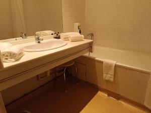 a bathroom with a sink and a bath tub at Logis Hotel La Bergerie in Saint-Pierre-Lafeuille