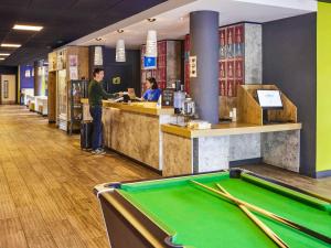 a man standing at a bar with a pool table at ibis budget Manchester Salford Quays in Manchester