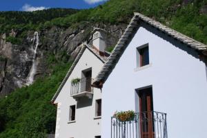 a white building with a waterfall in the background at Ca' del Borgo in Cadarese