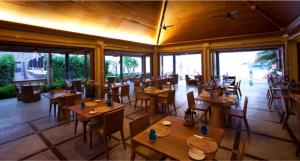 un restaurante con mesas y sillas de madera y ventanas en Deva Beach Resort Samui en Choeng Mon Beach