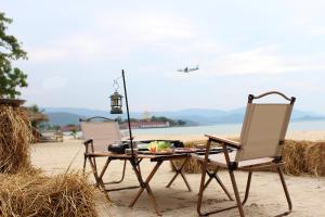 two chairs and a table and an airplane in the sky at Deva Beach Resort Samui in Choeng Mon Beach