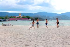 a group of men playing a game on the beach at Deva Beach Resort Samui in Choeng Mon Beach