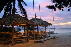 a beach with chairs and huts on the beach at Deva Beach Resort Samui in Choeng Mon Beach