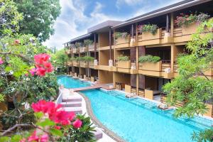 an apartment building with a swimming pool and flowers at Deva Beach Resort Samui in Choeng Mon Beach