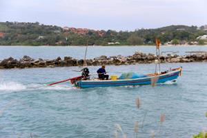 a man on a blue boat in the water at Deva Beach Resort Samui in Choeng Mon Beach