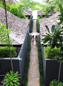 two children walking down a path in a garden at Deva Beach Resort Samui in Choeng Mon Beach