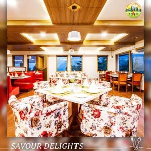 uma sala de jantar com mesa, cadeiras e janelas em Anand Vardhan Resorts em Manali