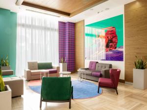 a waiting room with couches and chairs and a painting at ibis Styles Krasnaya Polyana in Estosadok