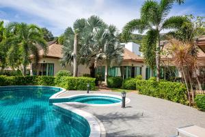 a swimming pool in front of a house with palm trees at Phuket Boutique Pool Villa-81 in Rawai Beach