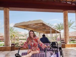 a woman sitting on a golf cart at a resort at Mövenpick Resort & Spa Tala Bay Aqaba in Aqaba