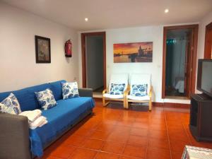 ein Wohnzimmer mit einem blauen Sofa und 2 Stühlen in der Unterkunft Casa Sevilla in Mairena del Aljarafe