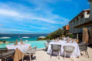 a restaurant with tables and chairs next to a swimming pool at Hotel Moresco in Santa Teresa Gallura