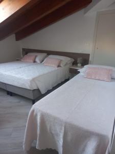 Duas camas num quarto com lençóis brancos e almofadas cor-de-rosa em Il Riccio home & relax em Riccia