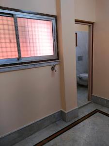 an empty bathroom with a window and a toilet at Kanan Villa in Kolkata