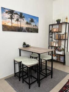 un tavolo e sgabelli in una stanza con palme di Zentrale gemütliche Wohnung a Saarbrücken