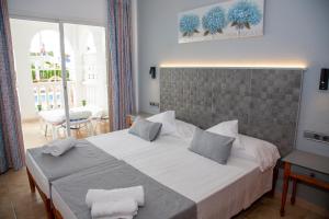 a bedroom with a large white bed with two pillows at Atalaya Bosque Apartamentos in Paguera