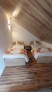drie bedden in een kamer met houten vloeren bij Noclegi w Dawnej Łaźni in Żarki