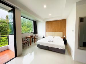 een slaapkamer met een groot bed en een tafel bij Kefir Phuket in Kamala Beach