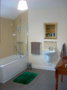 a bathroom with a tub shower and a sink at Templemoyle Farm Cottages in Campsey