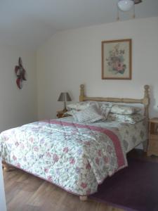 a bedroom with a bed with a floral comforter at Templemoyle Farm Cottages in Campsey
