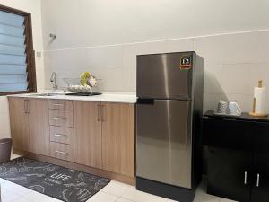 a kitchen with a stainless steel refrigerator and wooden cabinets at DOUBLETHREE Seroja Sepang in Sepang