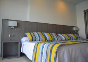 a bedroom with a large bed with striped pillows at Hotel Lido in Benidorm