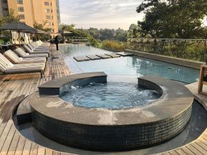 The Capital Sandton Luxury apartment with free pool, gym, spa and Netflix في جوهانسبرغ: مسبح مع حوض استحمام ساخن على سطح خشبي