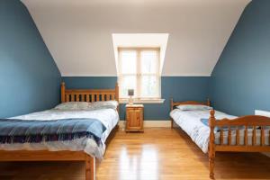 2 Betten in einem Zimmer mit blauen Wänden und Holzböden in der Unterkunft Ballinasloe in the Heart of the Country in Galway