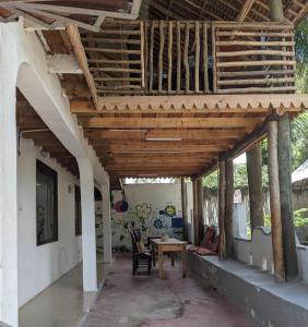 une terrasse couverte avec un toit en bois et une table dans l'établissement Cocobongo Beach Lodge, à Dar es Salaam