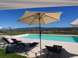 a group of chairs and an umbrella next to a swimming pool at SCAPPO IN UMBRIA, Casale in Castello delle Forme