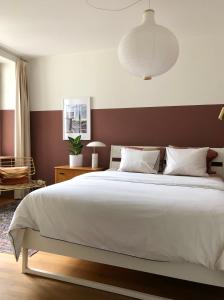 a bedroom with a large white bed with a brown wall at Historical, Bright & Beautiful in Old City - 3rd floor in Bern