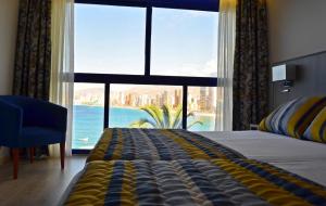 a bedroom with a large window with a view of the ocean at Hotel Lido in Benidorm