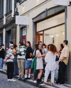 Un gruppo di persone che si trovano davanti alla finestra di un negozio di Jaca Hostel Funchal a Funchal