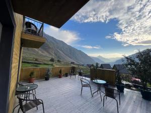 a balcony with tables and chairs and a view of mountains at UP in Kazbegi